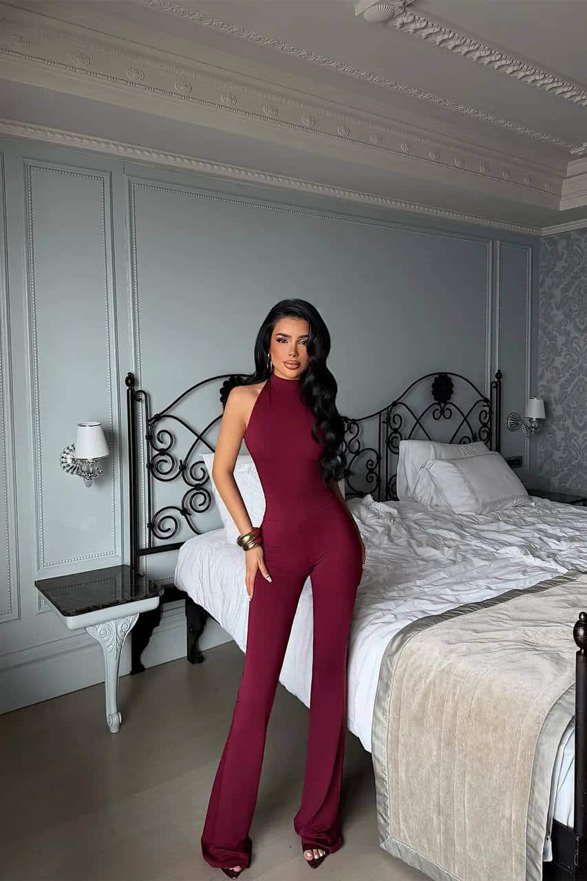 Combinaison Halter Bordeaux élégante Femme portant une combinaison halter bordeaux dans une chambre chic.
