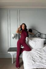Femme portant une combinaison halter bordeaux dans une chambre chic.
