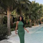 Femme portant une robe longue halter vert sauge près de la piscine.
